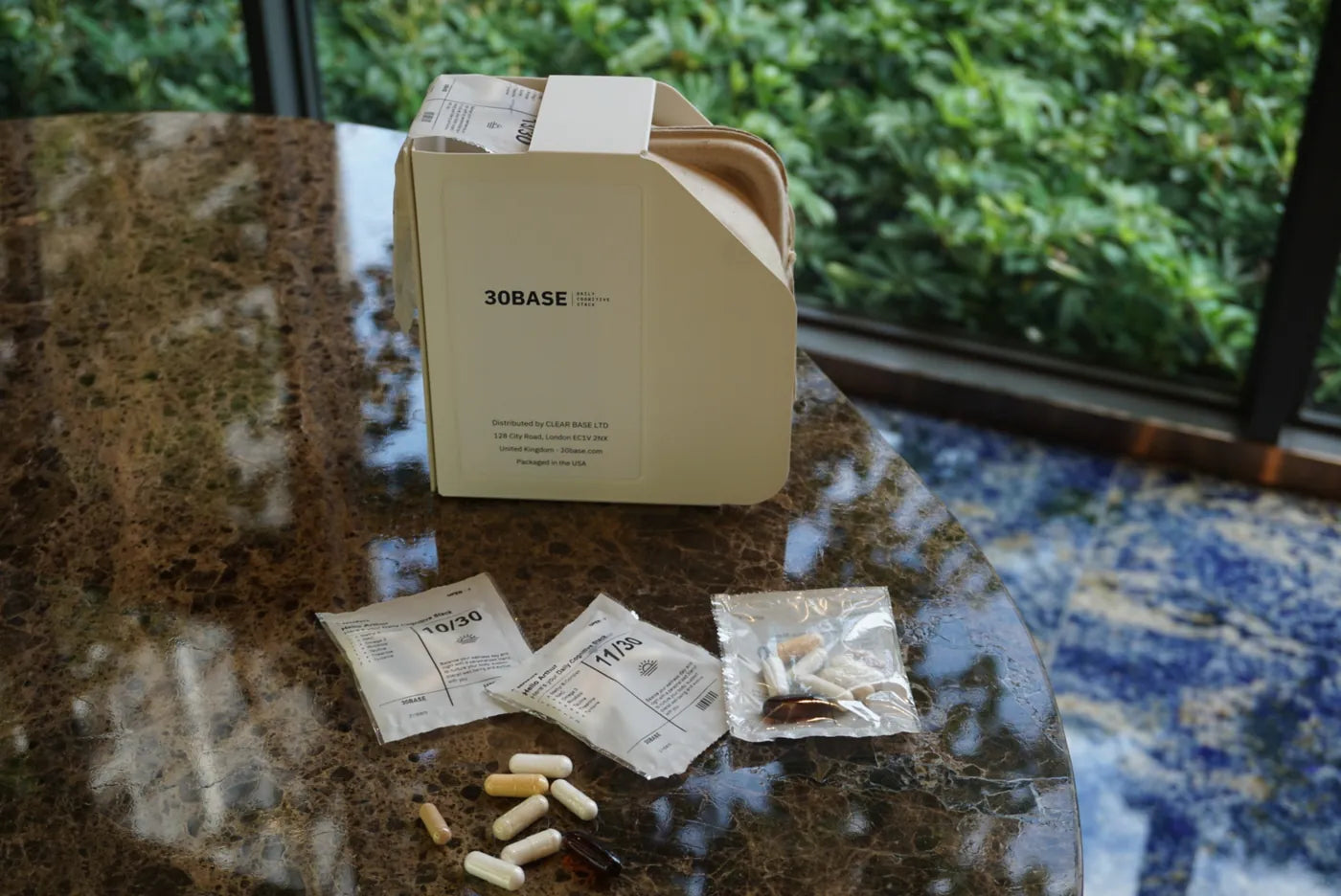 A 30BASE box beside its capsules poured out on granite.