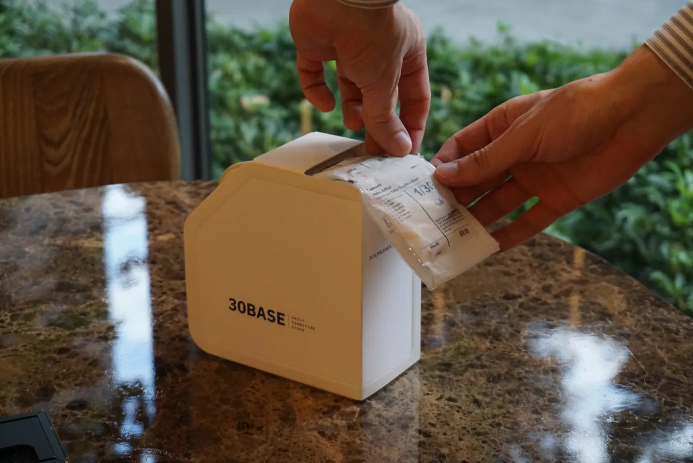 Two hands opening a 30BASE box outdoors.