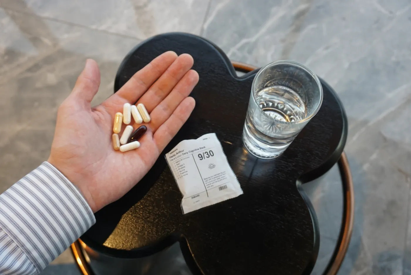 The daily capsules in an open palm next to a glass of water.