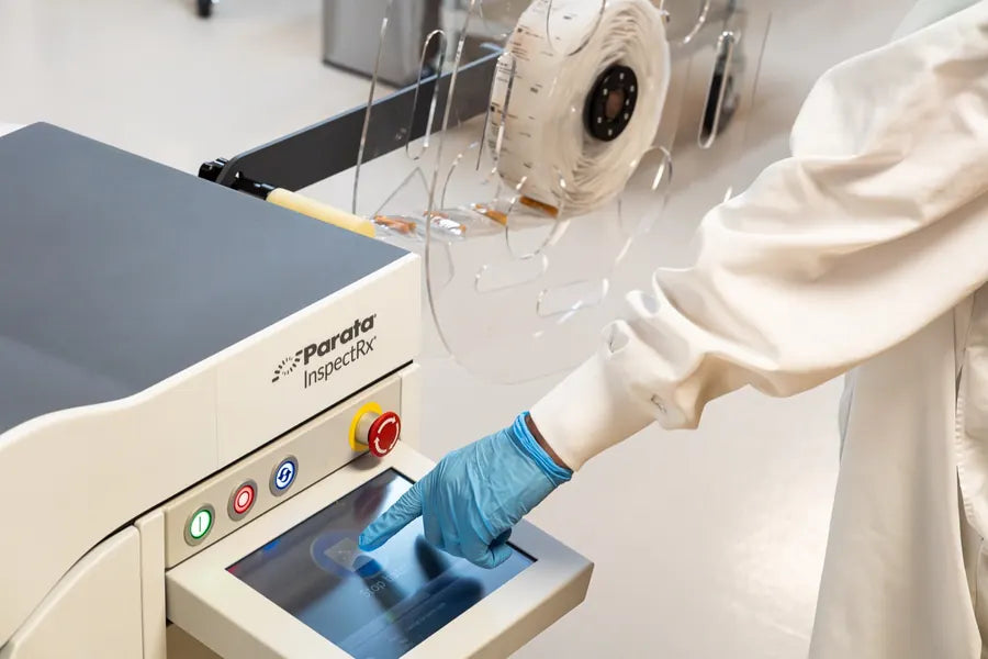 A gloved operator running the inline machine-vision inspection at the touchscreen.