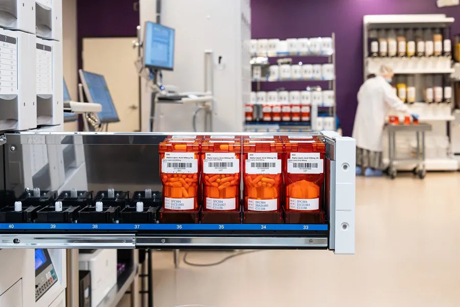 Labeled compound bottles in the automated dispensing system, an operator at work behind.