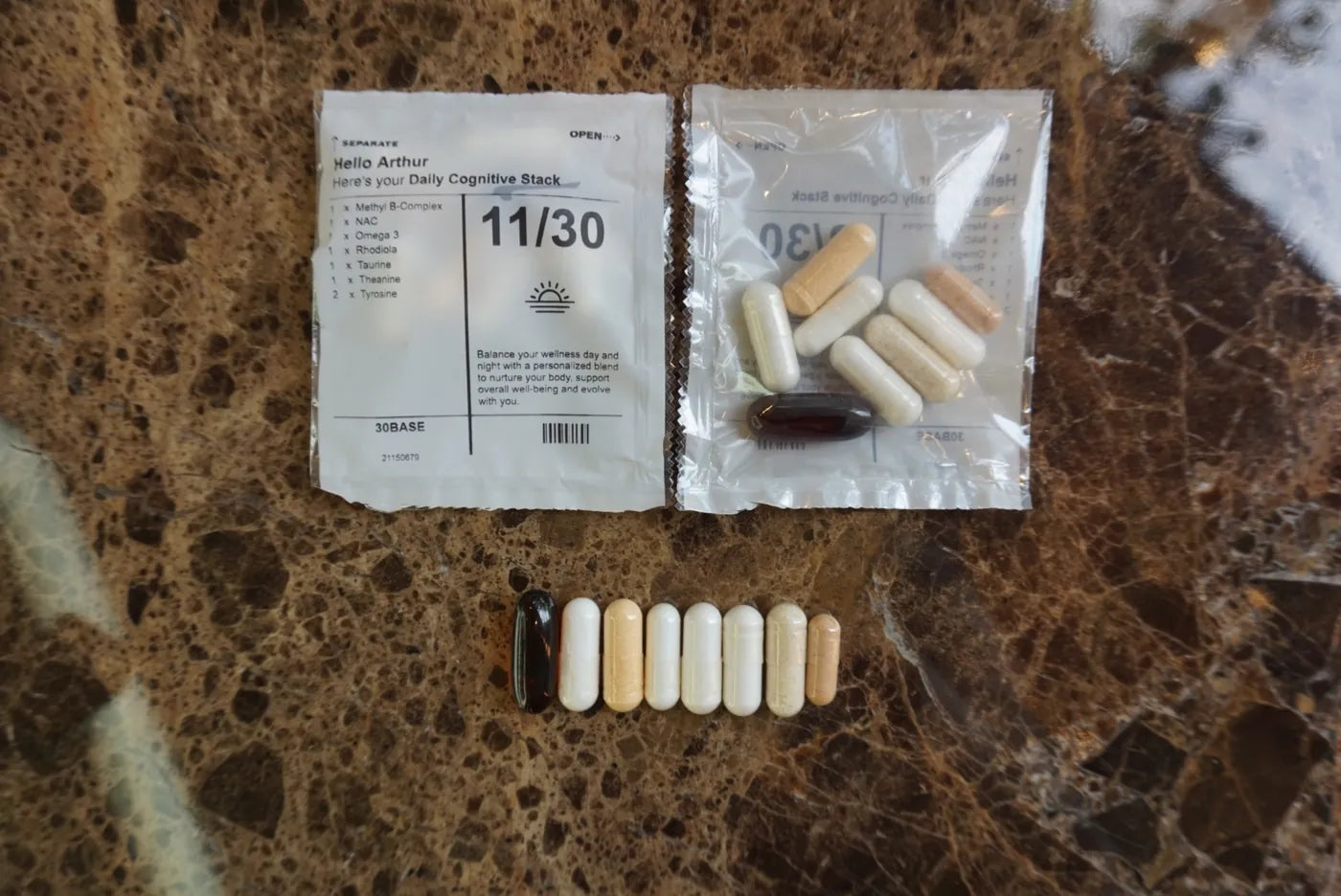 The eight daily capsules and a 30BASE sachet laid out on a granite surface.