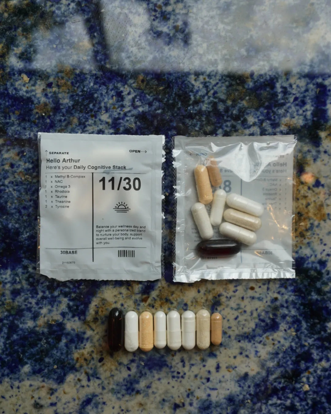Capsules from one 30BASE daily sachet on a granite surface next to the numbered sachet