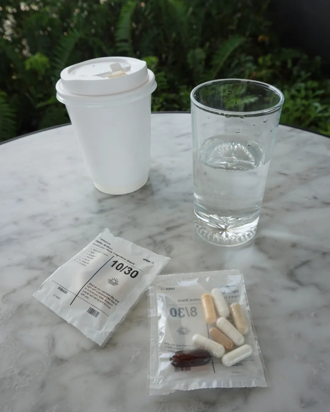 A 30BASE daily sachet opened on a cafe table, the capsules visible through the film