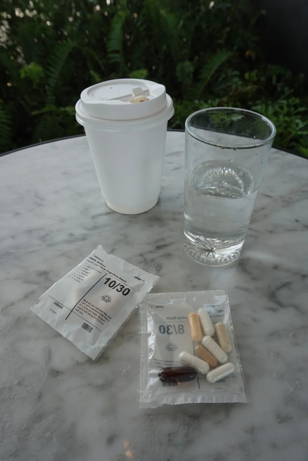 A 30BASE daily sachet beside a glass of water on a dark ledge.